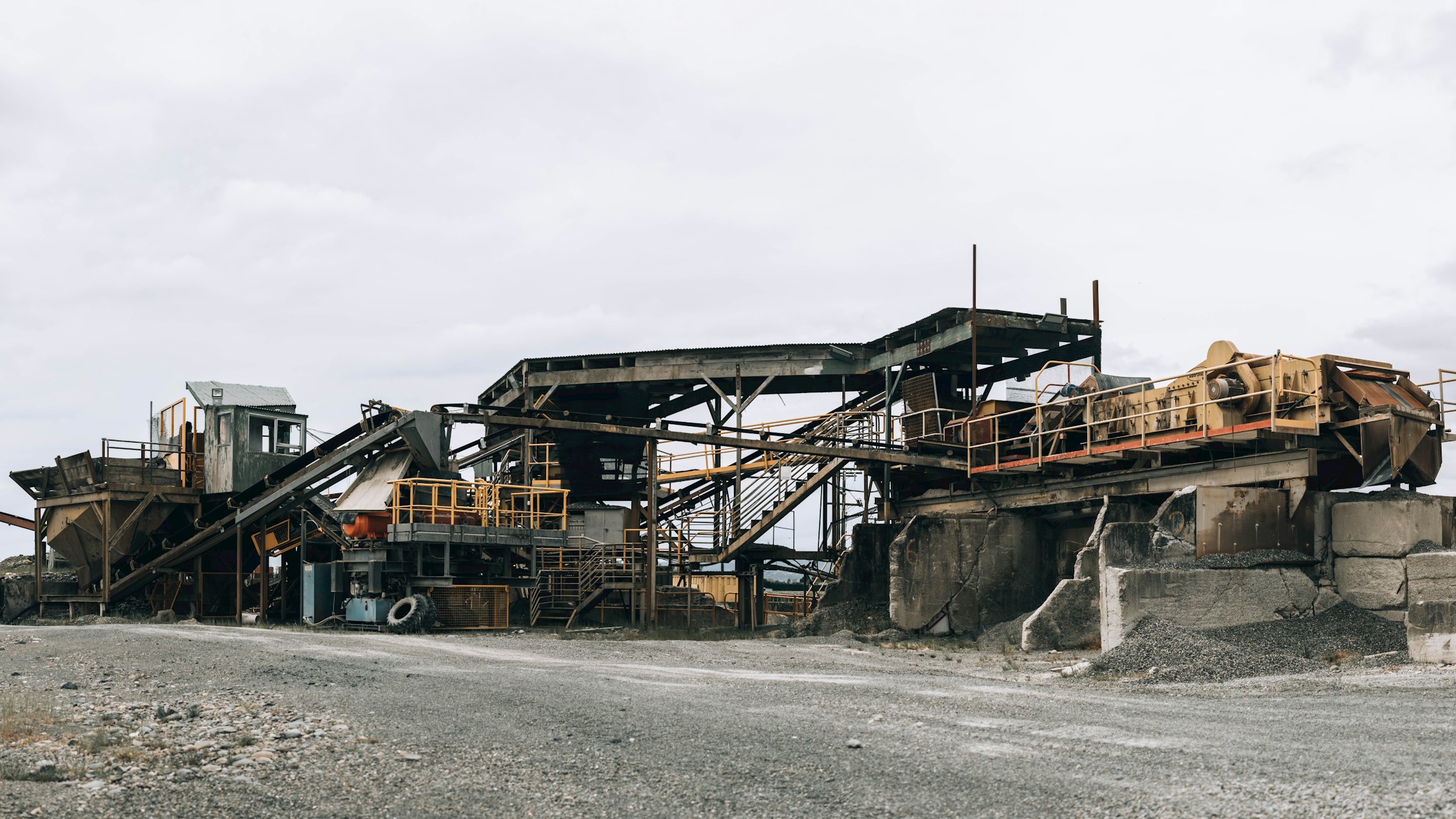 Graded aggregate crossing a vibrating screen deck, dust hanging in the air.