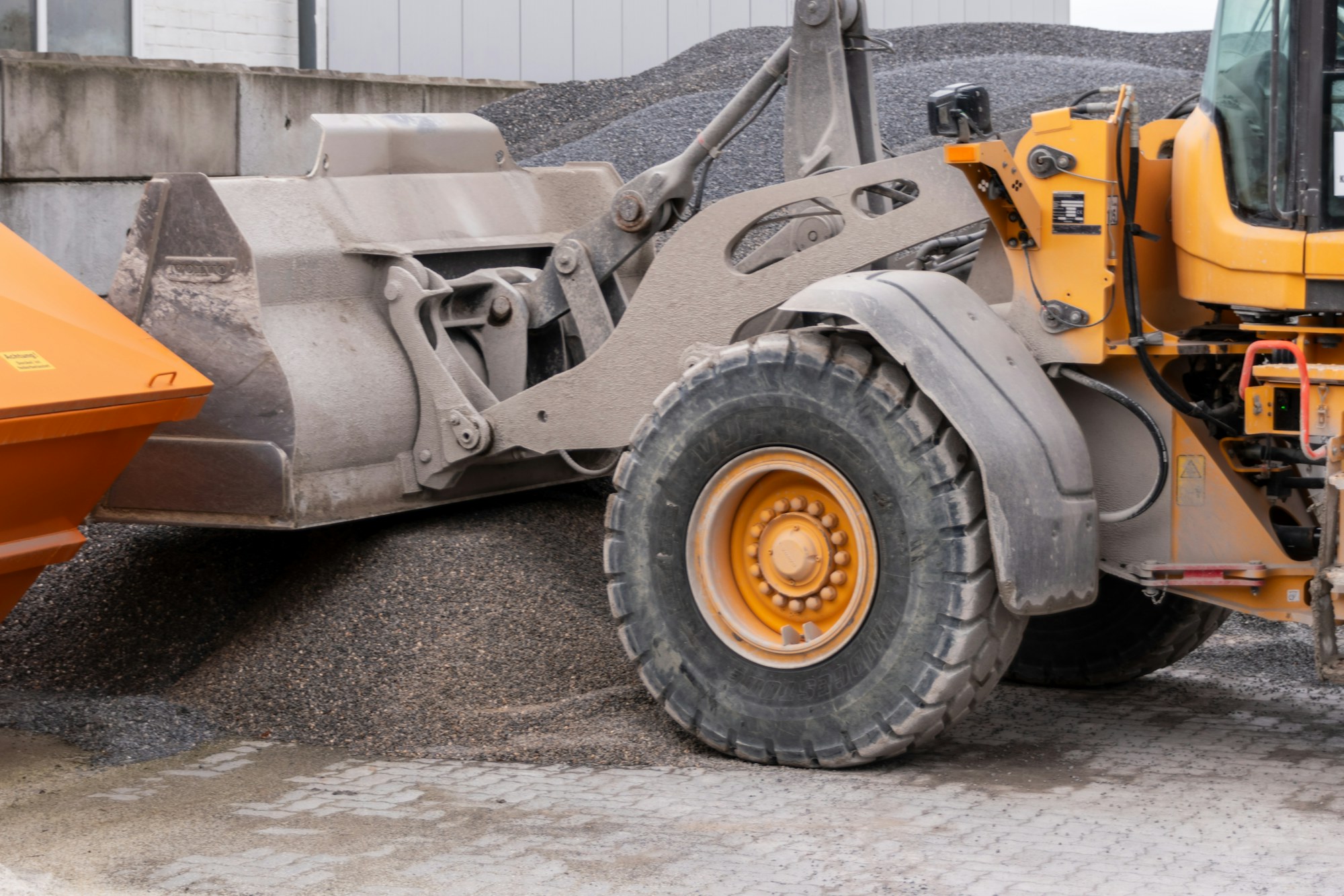 A wheel loader filling a haul truck with graded aggregate at the load-out.